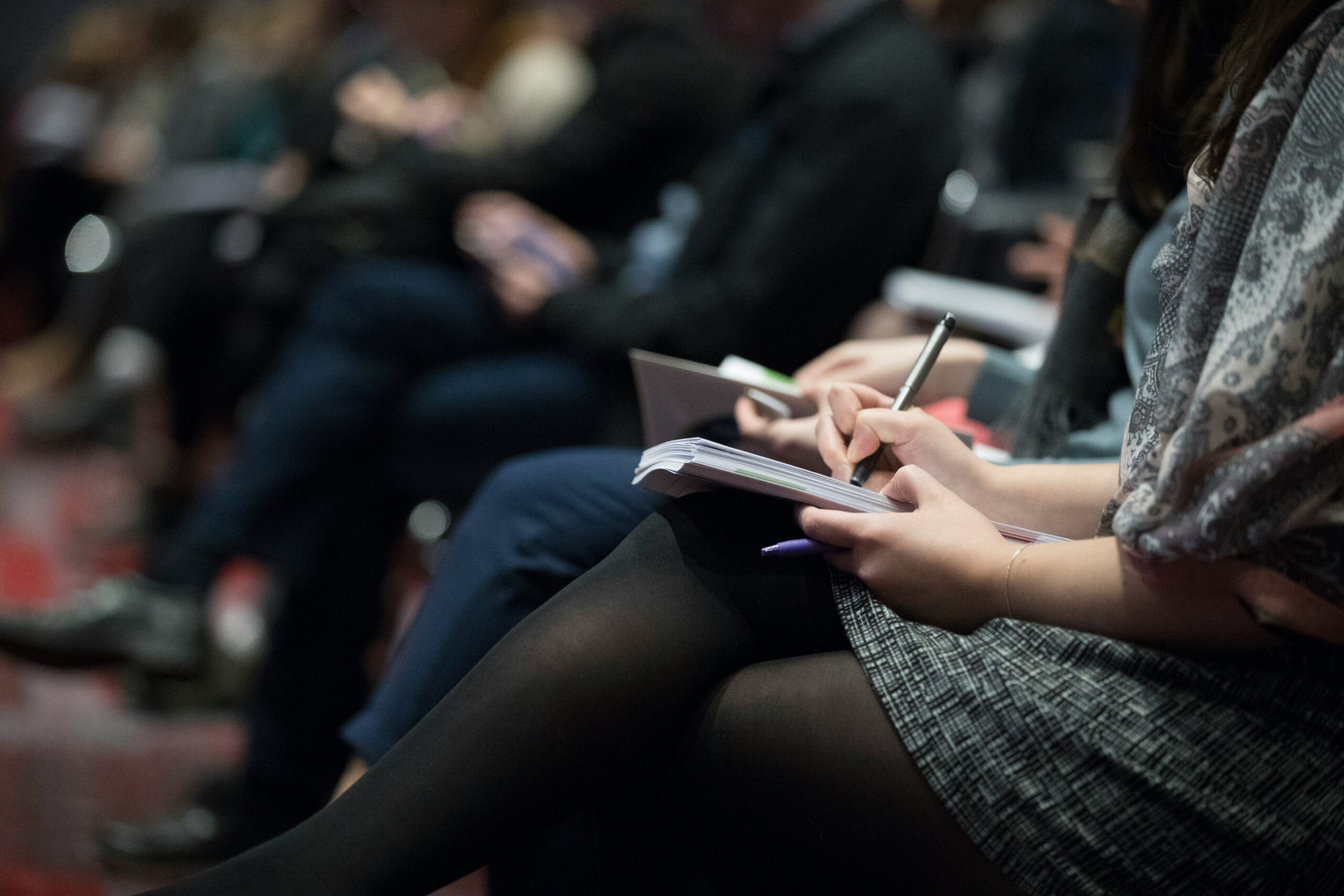 An image of a woman taking notes during a business meeting.