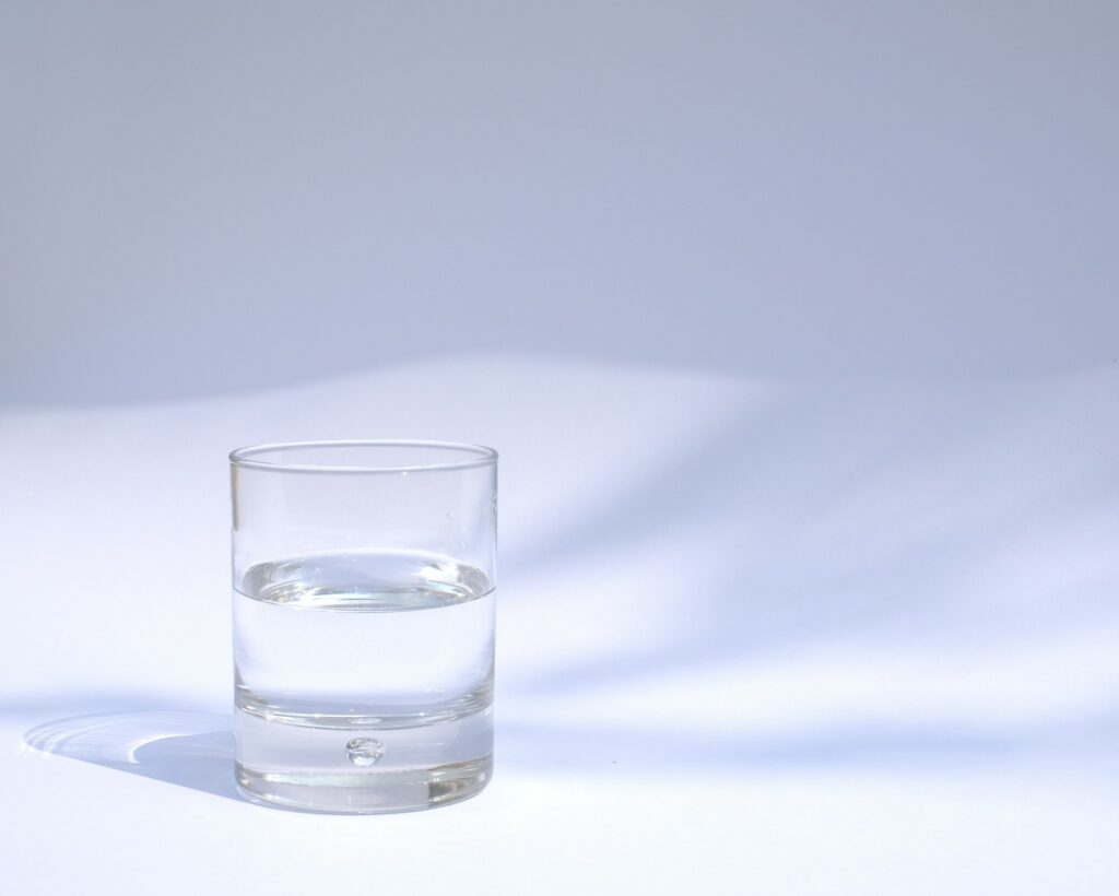 A clear glass of water on a white background, symbolizing the purity and high-quality standards of Enagic's certified water ionizers, delivering safe and effective hydration solutions.