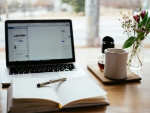 A workspace with a laptop and notebook symbolizes Darren and Mike, top Enagic distributors, sharing online business strategies with digital entrepreneurs.