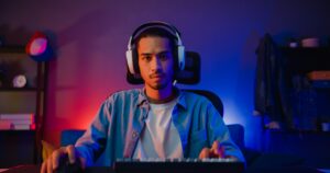 Focused young man wearing a headset at his computer, representing the determination and digital hustle of modern underdogs building online side businesses from home.