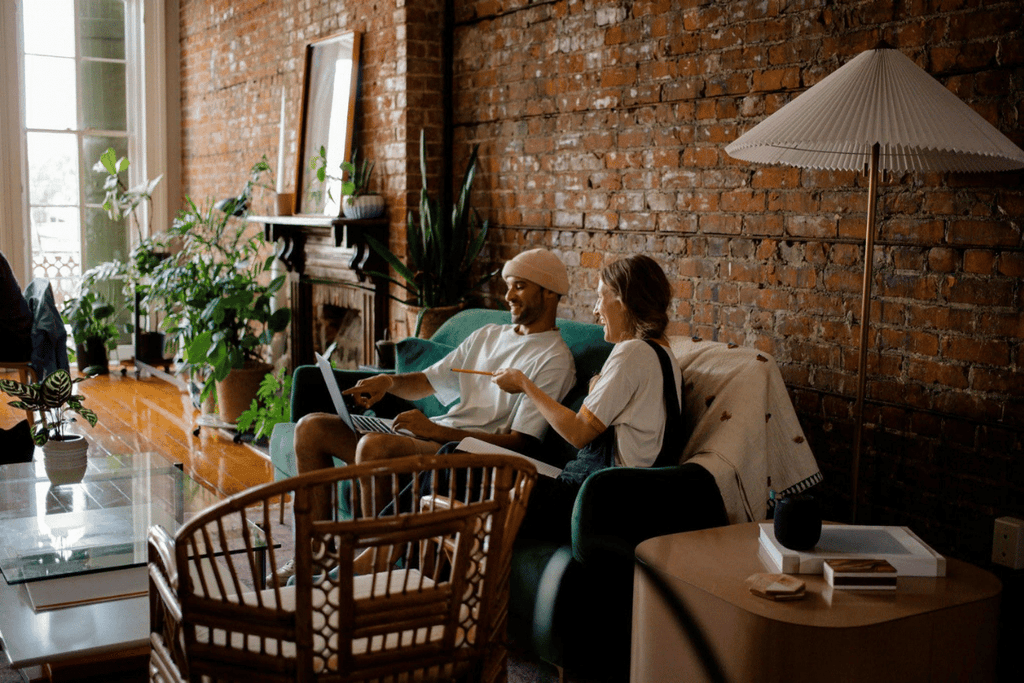 Young entrepreneurs collaborating on a laptop in a modern home office, discussing digital business strategies and online mentorship.