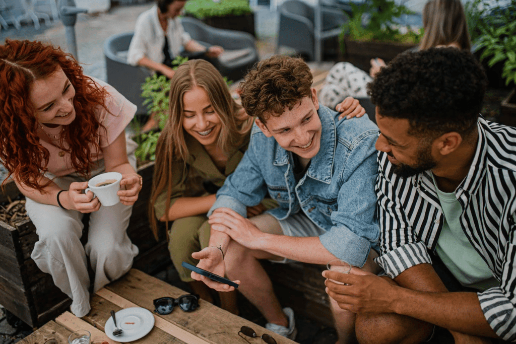 Young adults networking and laughing at an outdoor café, representing digital business and community